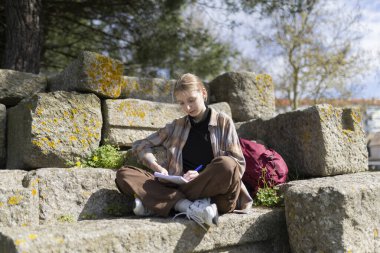 Arkeolojik kazı sırasında antik kalıntılarda otururken not defterine not alan kadın arkeolog.