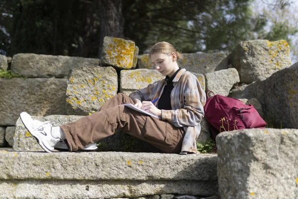 Arkeolojik keşifler sırasında antik kalıntılarda otururken not alan genç bir arkeolog.