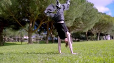 Parkta akrobatik hareketler yapan genç break dansçı, gösterisini alkışlarla bitiriyor.