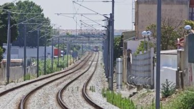 Güneşli bir günde banliyödeki tren rayları boyunca seyahat eden modern elektrik treni.