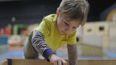 Eğitimsel bir oyun parkında interaktif bir sergiyle oynayan odaklanmış küçük bir çocuk