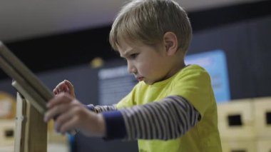 Etkileşimli bir müzede oyun oynayarak öğrenmeye odaklanmış küçük bir çocuk.