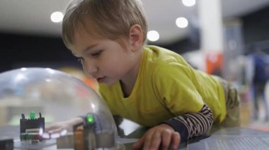 Sevimli çocuk modern bir bilim müzesinde interaktif bir sergi açıyor ve onunla oynuyor.