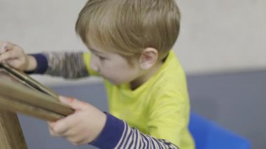 Genç sarışın çocuk anaokulundaki dijital tablette eğitici bir oyuna daldı.