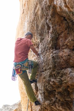 Adam engebeli bir uçuruma tırmanıyor, dışarıda tutunmaya çalışıyor.