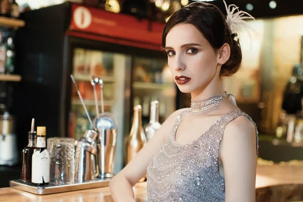 Close-up portrait of a young attractive woman in a 1920s style at the bar. Model with a beautiful make-up