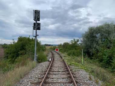 Gaenserndorf, Aşağı Avusturya: Demiryolu Sinyal direğinin arkası ve kırmızı dikdörtgen kapama sembolüyle kapalı OeBB demiryolu rayları. Tırabzanlar ve ahşap kravatlar yavaşça yabani otlarla kaplı..