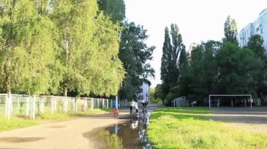 Çocuklar okul stadyumunda bisiklete biniyorlar.