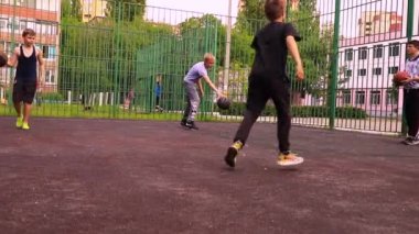 Çocuklar okul bahçesinde maskesiz basketbol oynuyorlar.