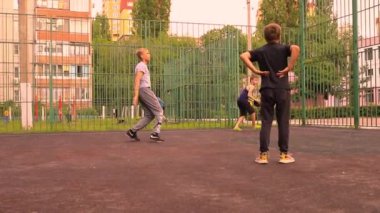Çocuklar okul bahçesinde maskesiz basketbol oynuyorlar.