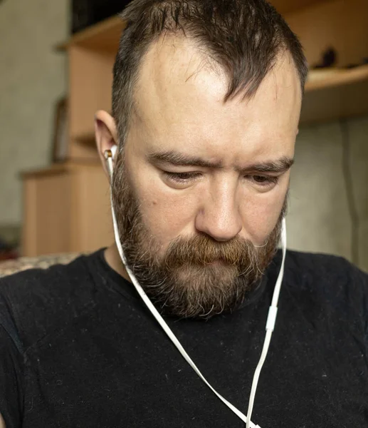 Yakışıklı sakallı adam kulaklıkla oturur ve dikkatle dinler ve cihazında ne yayınlandığını izlerim. Sıradan bir dairenin içinde.