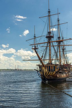 Yelkenli rıhtımda. Büyük gemi Peter ve Rusya 'nın ilgi odağı. Onun üstünde de gökyüzü, bulutlar var. Geminin sudaki yansıması.