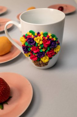 Dekoratif figürlerle kendi elleriyle yapılmış orijinal kupa. Güzel bir doğum günü hediyesi. Fincandaki figürler renkli kilden yapılmış el yapımı. Tabaklarda meyveler olan kompozisyon