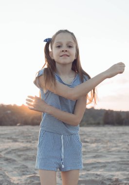Küçük bir kız sahilde eğleniyor ve eğleniyor. Yukarıda mavi bir gökyüzü ve bir sürü yer var.