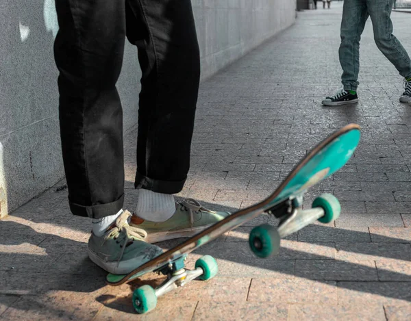 Şehir yürüyüşü. Siyah kotlu genç bir adam kaykayın üzerinde duruyor. Fotoğraf hızlı hareketi gösteriyor..