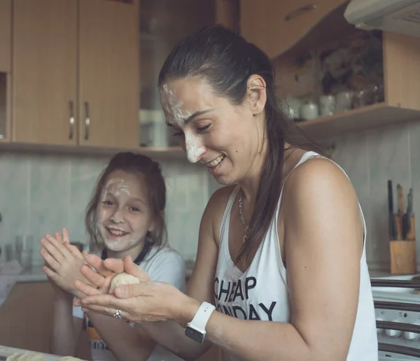 Anne ve kızı mutfakta eğleniyor ve birlikte yemek pişiriyorlar. Neşeli ve güzeller.