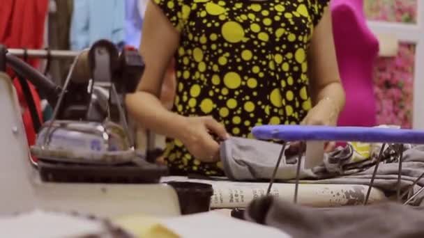 A professional seamstress at work in his workshop. She crafts her work with skilful hand movements with threads and tools. — Stock Video