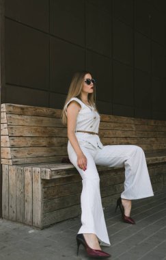 Bankta oturan güzel beyaz bir kızın portresi. Pahalı bir takım elbise ve makyaj yapıyor. Oturmuş birini bekliyor.