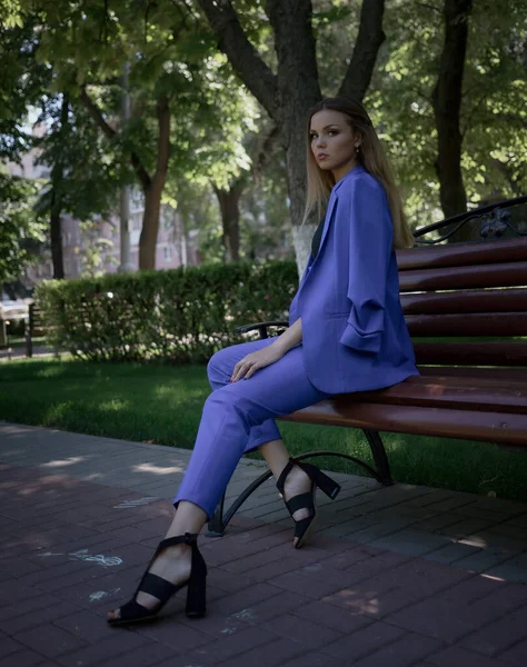 Bankta oturan güzel beyaz bir kızın portresi. Pahalı bir takım elbise ve makyaj yapıyor. Oturmuş birini bekliyor.