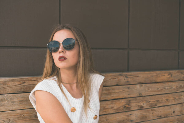 Portrait of a beautiful white girl who sits on a bench. Shes wearing an expensive suit and make-up. She sits waiting for someone