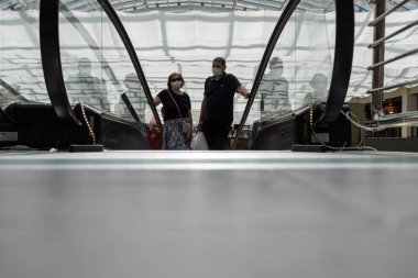 Salgın sırasında bir alışveriş merkezinde yürüyen merdiven. İnsanlar sadece maksimum düzeyde hareket ederler.