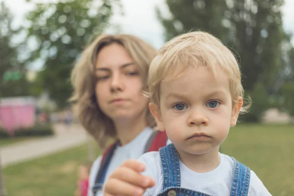 Mamá y su hijo caminan en el parque en trajes de mezclilla idénticos. disfrutan del tiempo juntos y se aman — Foto de Stock
