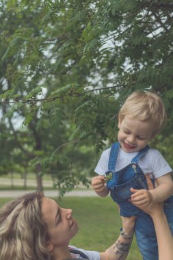 Anne ve oğlu aynı kot tulumlarla parkta yürüyorlar. Birlikte vakit geçirip birbirlerini seviyorlar.