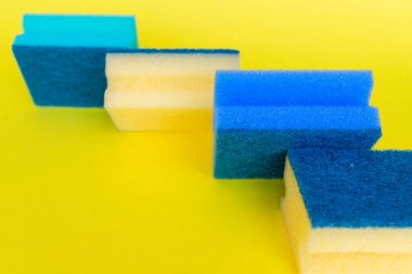 Sarı arka planda farklı renkte bulaşık süngeri var.