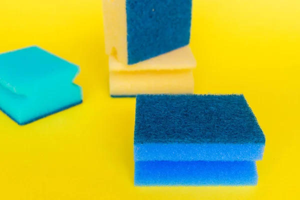 Sarı arka planda farklı renkte bulaşık süngeri var.