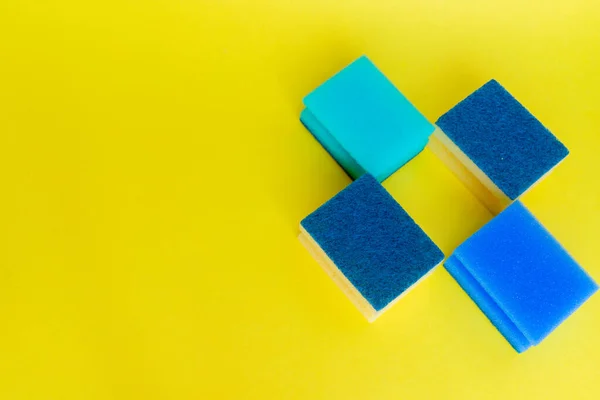 Sarı arka planda farklı renkte bulaşık süngeri var.