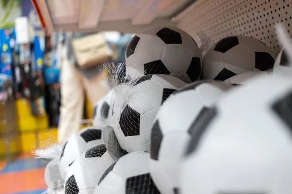 Rafta bir sürü siyah beyaz futbol topu var.