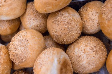 Bir kaç taze pişmiş hamburgerin üzerine susam tohumu serpiştirilmiş.