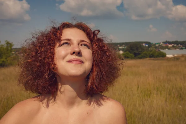 Köyde poz veren, kızıl saçlı, kıvırcık saçlı, yazlık elbiseli kız. 