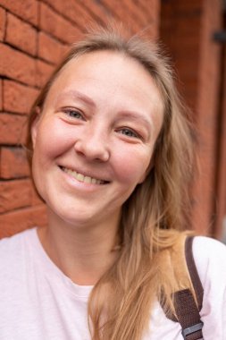 Beyaz tişörtlü ve kot pantolonlu güzel bir kız şehrin sokaklarında poz veriyor. Uzun saçları var ve makyajı yok. Eski şehrin mimarisi onun etrafında bir zemin.