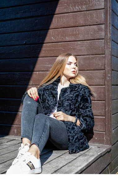 Uzun saçlı ve anlamlı gözlü güzel bir kız parkta kürk giymiş poz veriyor.