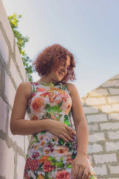 Vermelho de cabelos encaracolados menina em um vestido de verão posando na aldeia — Fotografia de Stock