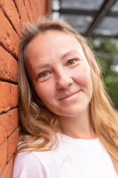 Beyaz tişörtlü ve kot pantolonlu güzel bir kız şehrin sokaklarında poz veriyor. Uzun saçları var ve makyajı yok. Eski şehrin mimarisi onun etrafında bir zemin.