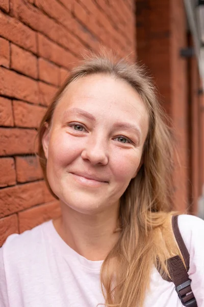 Beyaz tişörtlü ve kot pantolonlu güzel bir kız şehrin sokaklarında poz veriyor. Uzun saçları var ve makyajı yok. Eski şehrin mimarisi onun etrafında bir zemin.