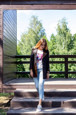 Uzun saçlı ve anlamlı gözlü güzel bir kız parkta kürk giymiş poz veriyor.