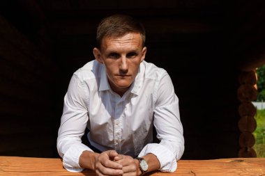 Beyaz gömlekli, Avrupalı yakışıklı bir adam köyde poz veriyor.