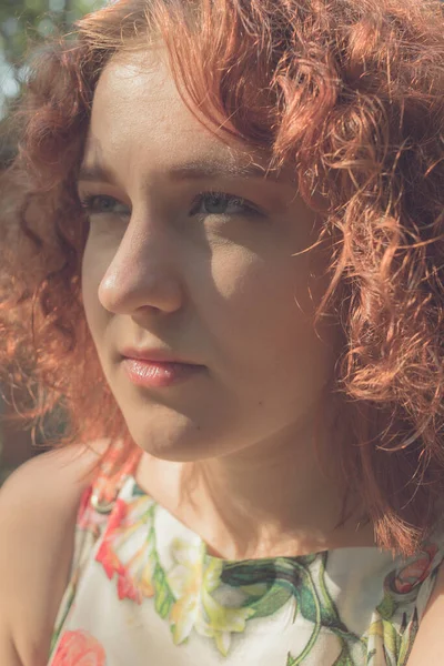 Vermelho de cabelos encaracolados menina em um vestido de verão posando na aldeia — Fotografia de Stock