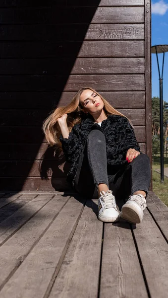 Uzun saçlı ve anlamlı gözlü güzel bir kız parkta kürk giymiş poz veriyor.