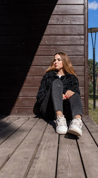 Uzun saçlı ve anlamlı gözlü güzel bir kız parkta kürk giymiş poz veriyor.