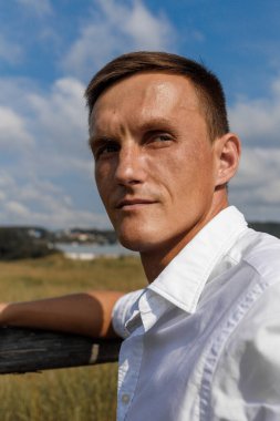 Beyaz gömlekli, Avrupalı yakışıklı bir adam köyde poz veriyor.