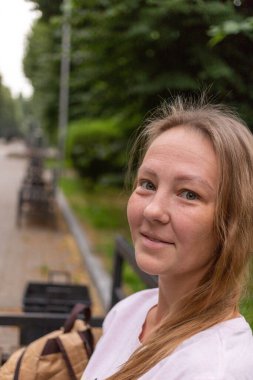 Beyaz tişörtlü ve kot pantolonlu güzel bir kız şehrin sokaklarında poz veriyor. Uzun saçları var ve makyajı yok. Eski şehrin mimarisi onun etrafında bir zemin.