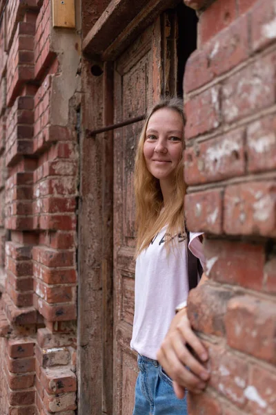 Beyaz tişörtlü ve kot pantolonlu güzel bir kız şehrin sokaklarında poz veriyor. Uzun saçları var ve makyajı yok. Eski şehrin mimarisi onun etrafında bir zemin.