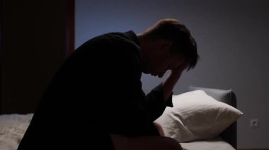 Depresyonda olan genç bir adam geceleri yatağında oturup elleriyle yüzünü kapatıyor. Yalnızlık, depresyon, stres, duygusal sorunlar, keder ya da akıl sağlığı sorunları yaşıyor.