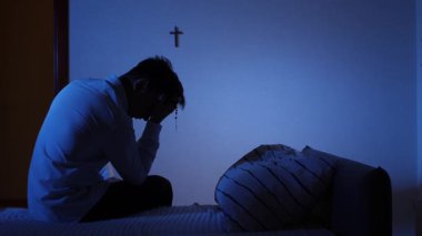 Hıristiyan Adam karanlık bir odada gece bir yatakta oturuyor, elinde bir tespih tutuyor, başı öne eğik dua ediyor, manevi mücadeleyi, yalnızlığı ve duygusal umutsuzluğu yansıtıyor.