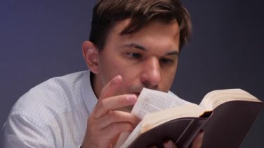 Man holding an open book, intently reading and concentrating on the text, focused on learning, study or spiritual reflection, thoughtful and engaged in quiet study
