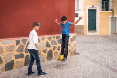 Açık havada sokakta futbol topuyla oynayan çocuklar